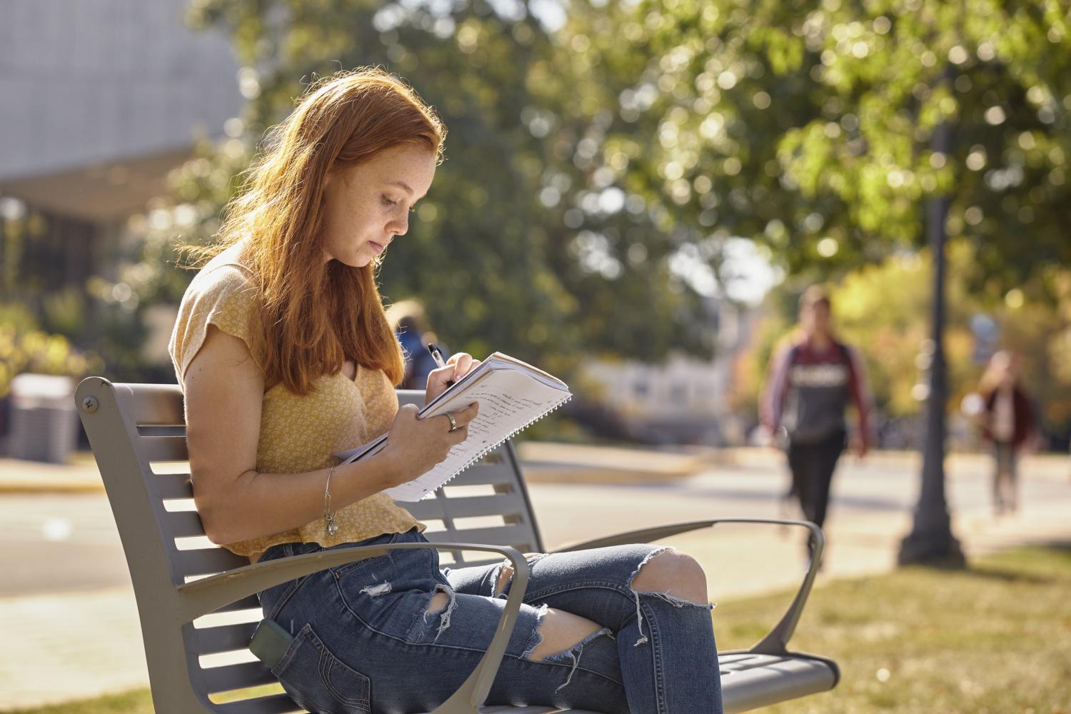 一位<a href='http://hg0y.orkexpo.net'>bv伟德ios下载</a>学院的学生在校园里的长椅上读书.